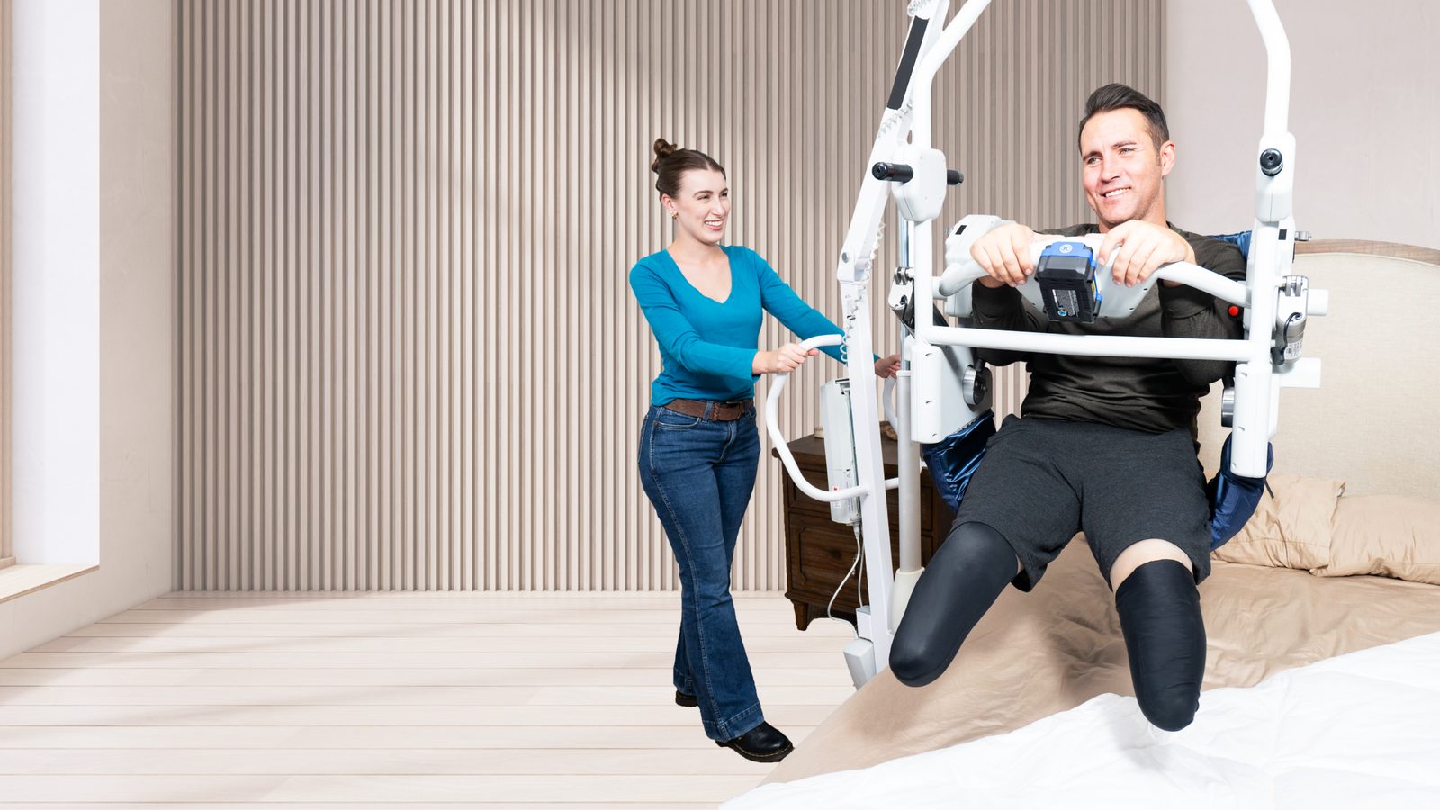 A man transferring from bed into a seated position with UpLyft while a caregiver assists